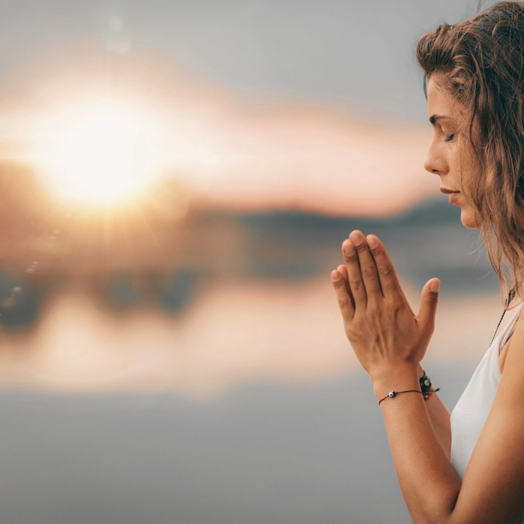 woman with prayer hands and light burst